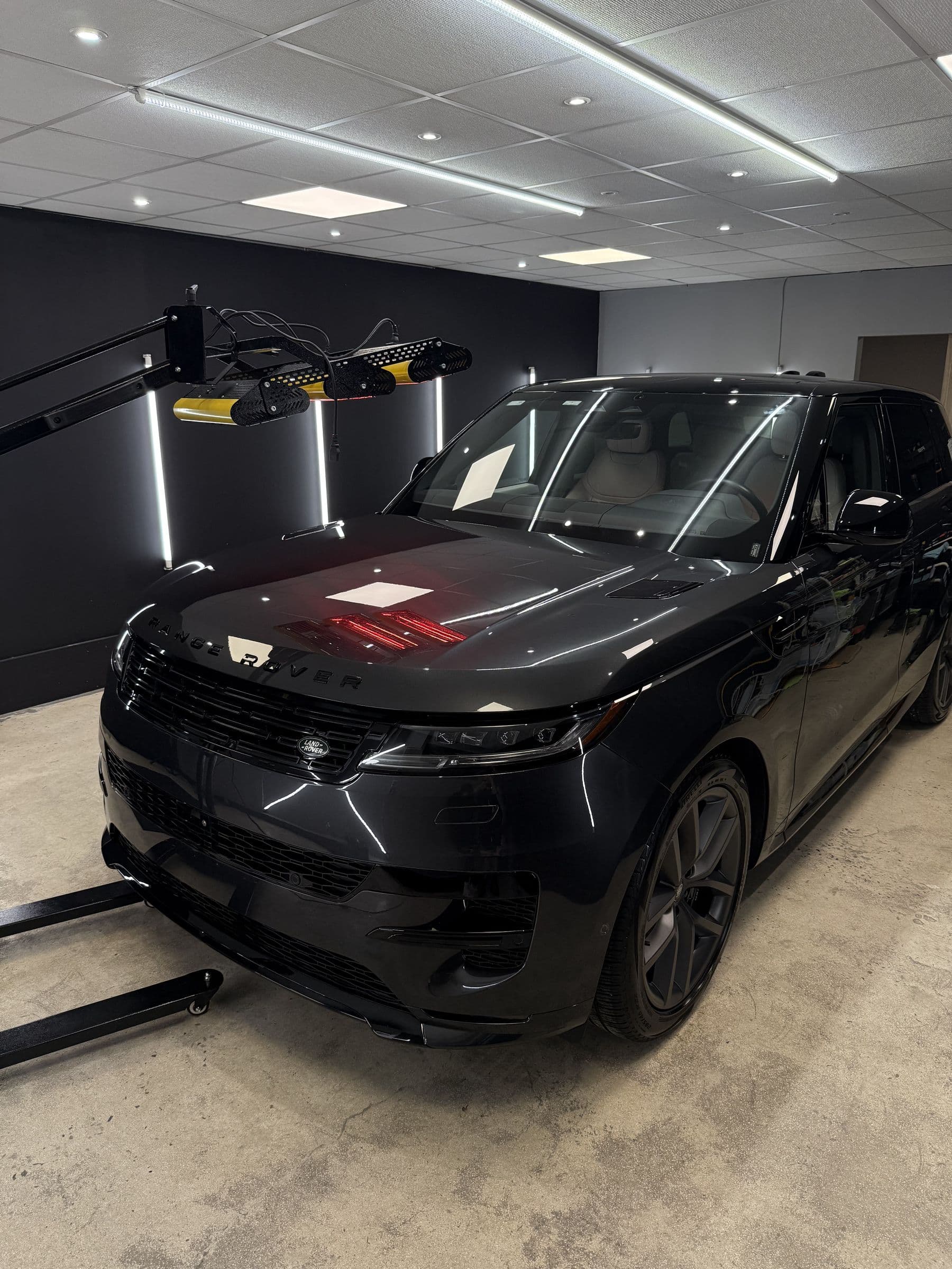 Range Rover negro en el bay de RB CAR CARE bajo la lámpara infrarroja de curado